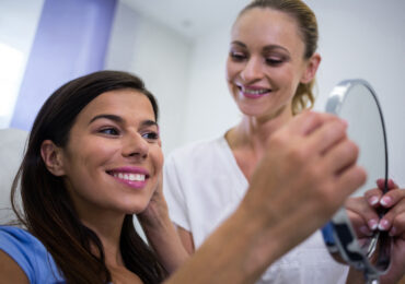 Happy woman excited to see herself in the mirror after getting her work done at the dentist.